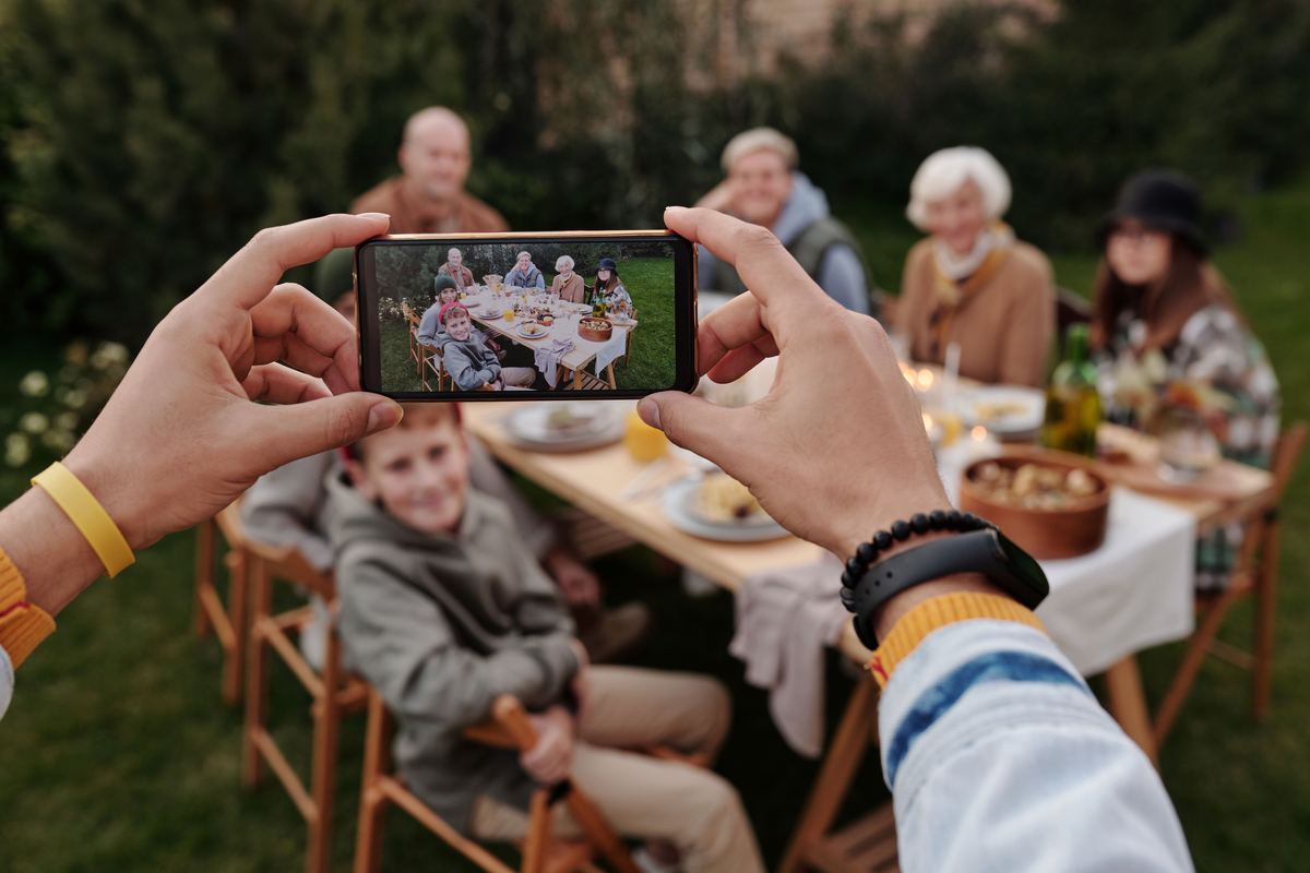 Family photographing a multi-generation reunion dinner outdoors