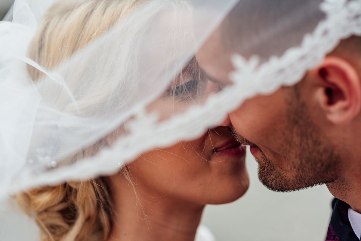 Bride and groom together under a veil on their wedding day